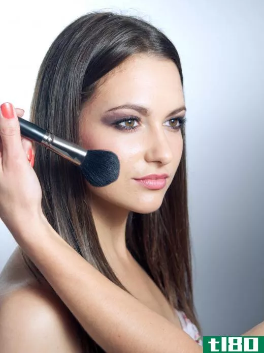 A woman wearing black eyeliner has blush applied.
