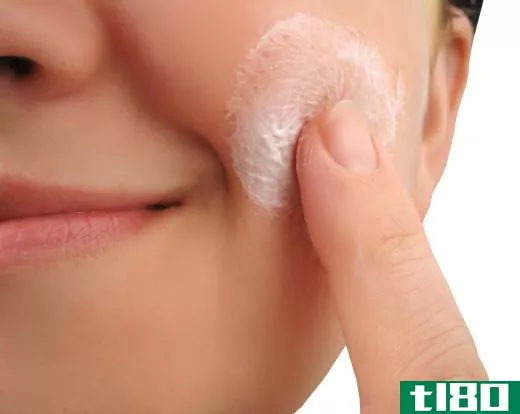 A woman putting lotion on her face.
