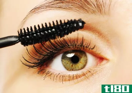 A woman applying conditioning mascara to her eyelashes.