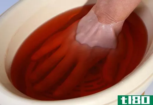 A woman dipping her hand in melted paraffin.