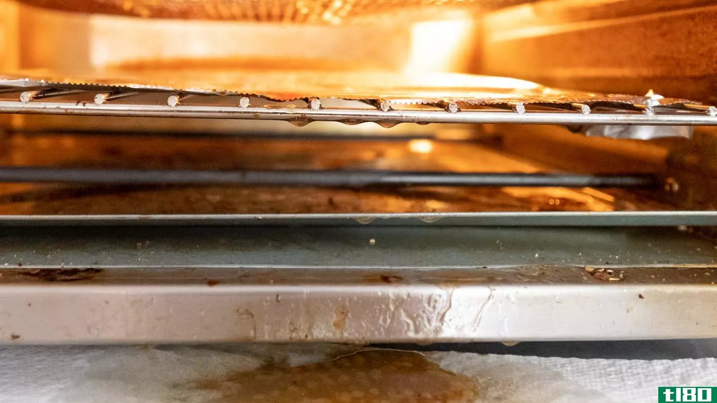 Front-facing photo of a countertop convection oven. There's grease dripping off the middle rack, bottom tray, and all the way out onto the counter. 