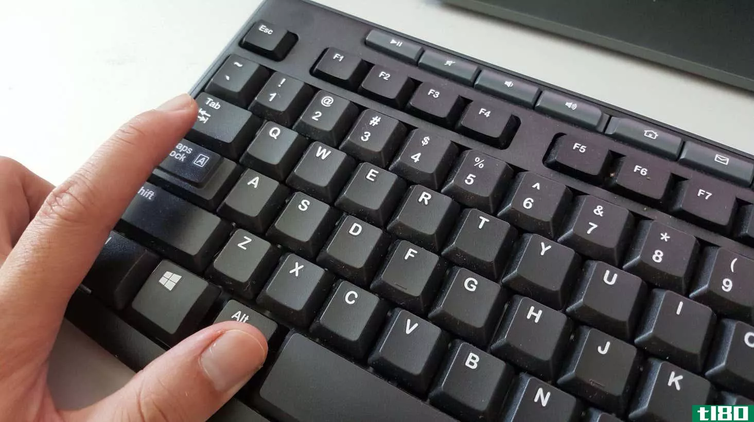 A hand presses alt+tab on a Windows keyboard