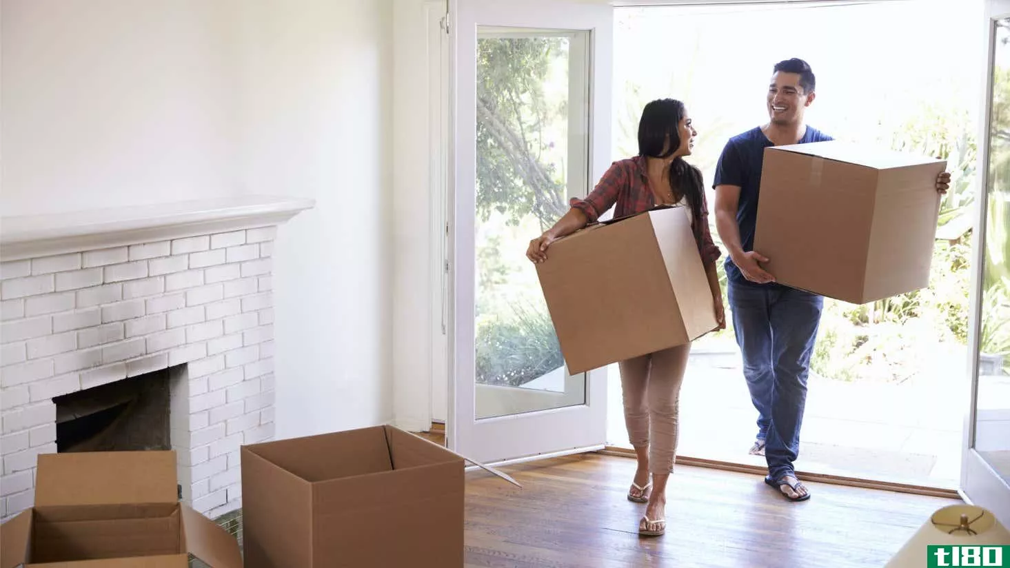 couple carrying boxes into new house