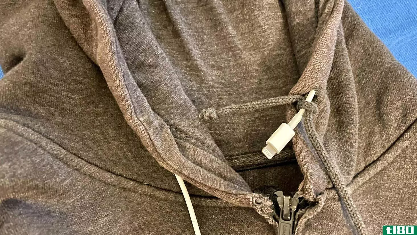 iPhone cable through hoodie drawstring channel, with the drawstring tied around it just before being pulled through.
