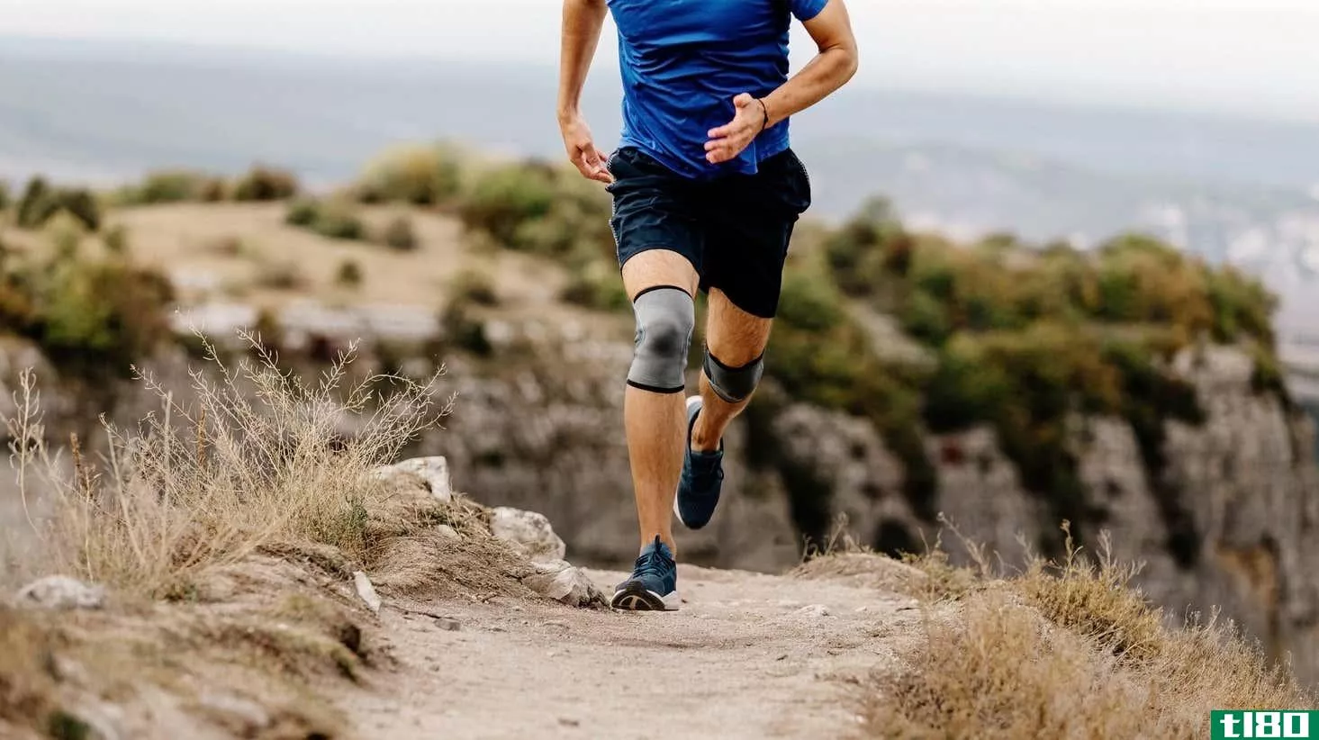 Runner wearing knee braces running on a trail
