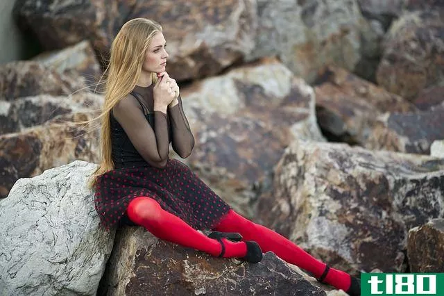 woman sitting on rocks wearing a black dress and red tights