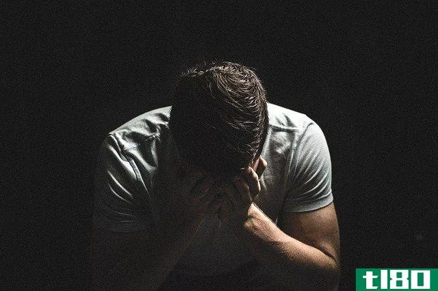 man with his head down against black background