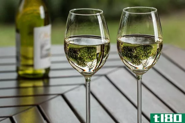 two glasses of white wine on a wooden table