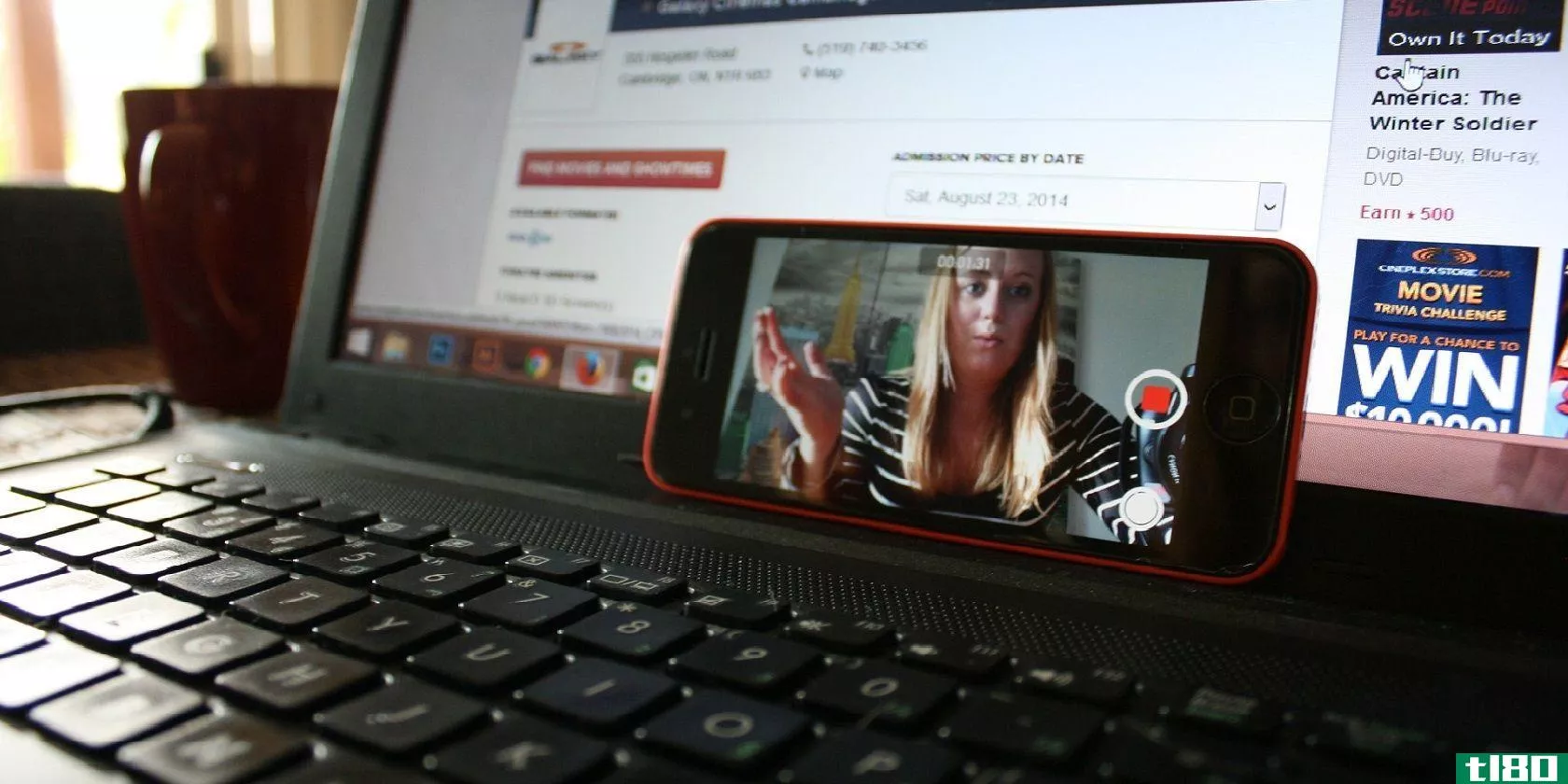 a woman recording a video on an iphone propped on an open laptop