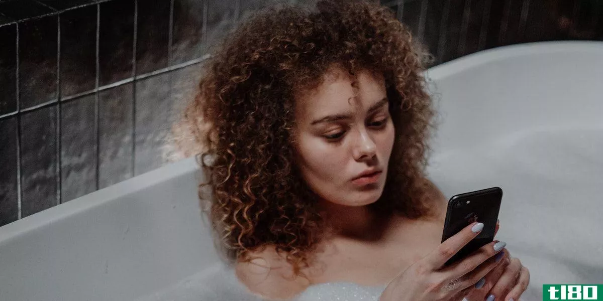 Woman sitting in a bubblebath using her phone