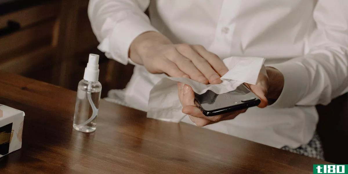 Cleaning a phone while wearing a dress shirt at a wooden table