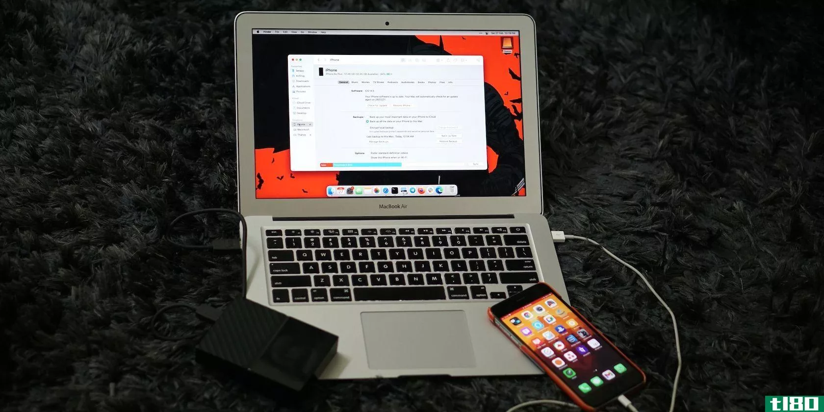 An iPhone resting on a MacBook while completing a backup.