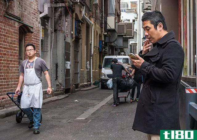 Man Smoking Cigarette on Phone in Alley