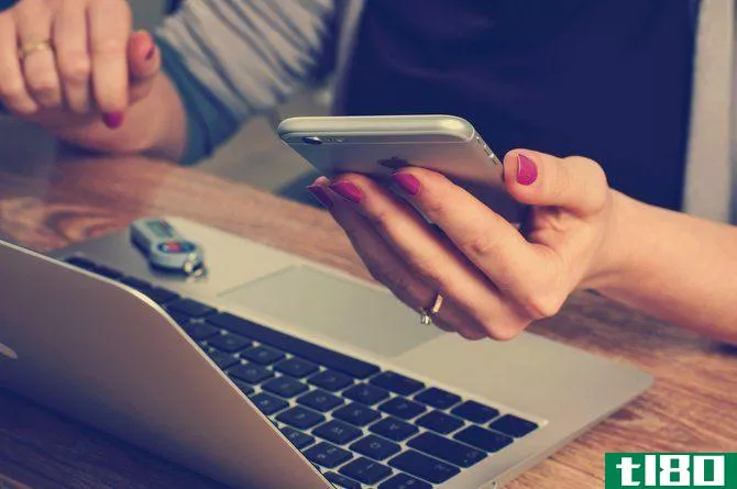 Woman looking at phone while at computer