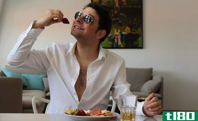 This is a picture of a guy eating breakfast and wearing sunglasses indoors