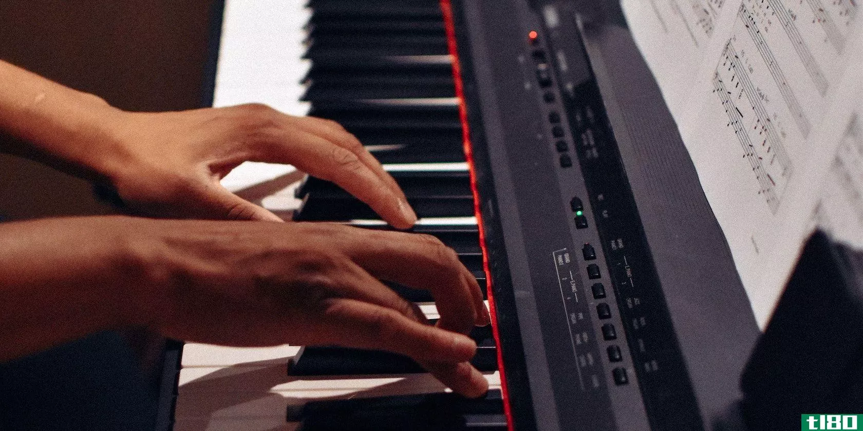 A person playing a keyboard with both hands and with sheet music and a red light and green light on.