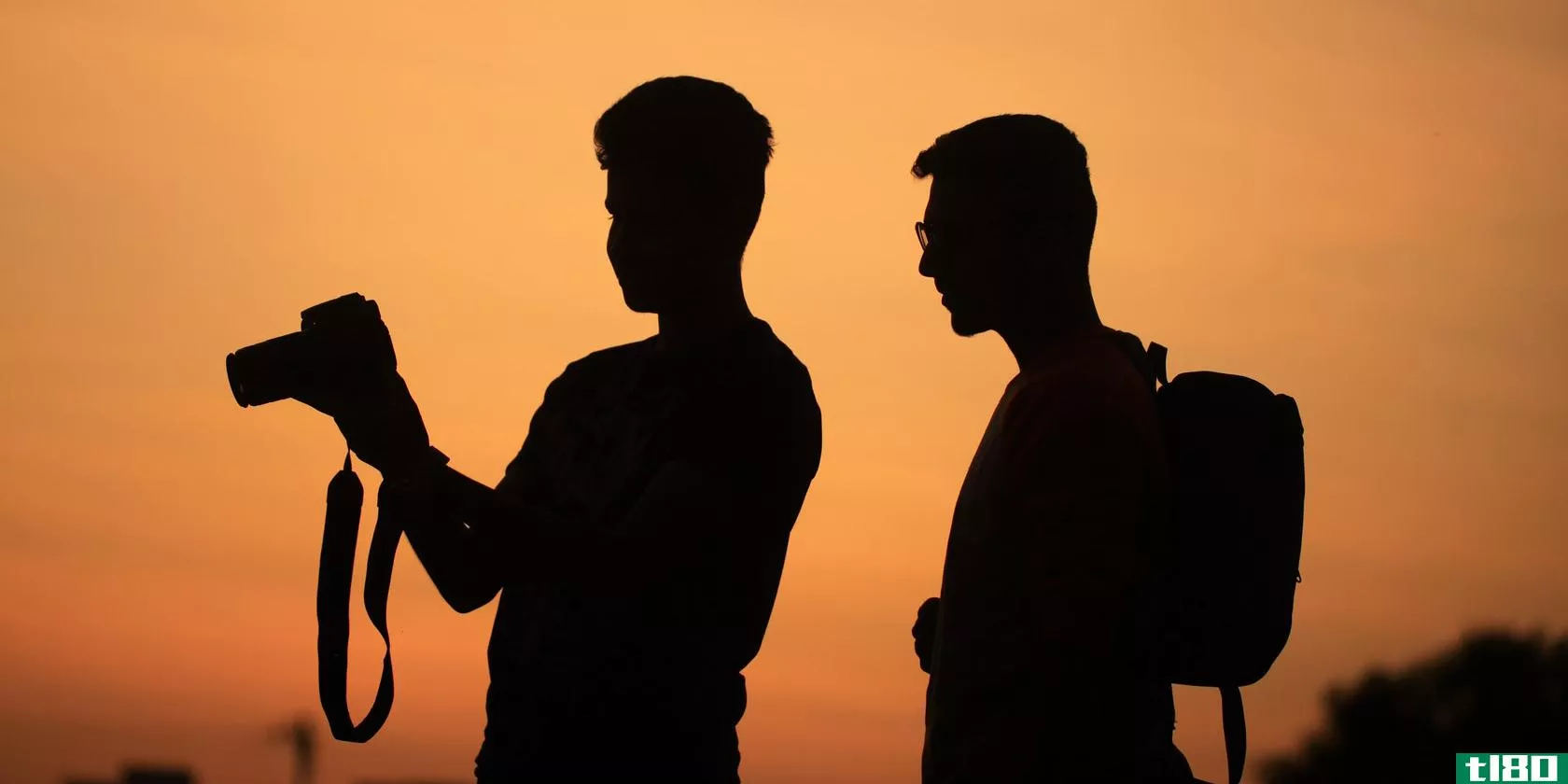 The silhouettes of two guys, one holding a camera