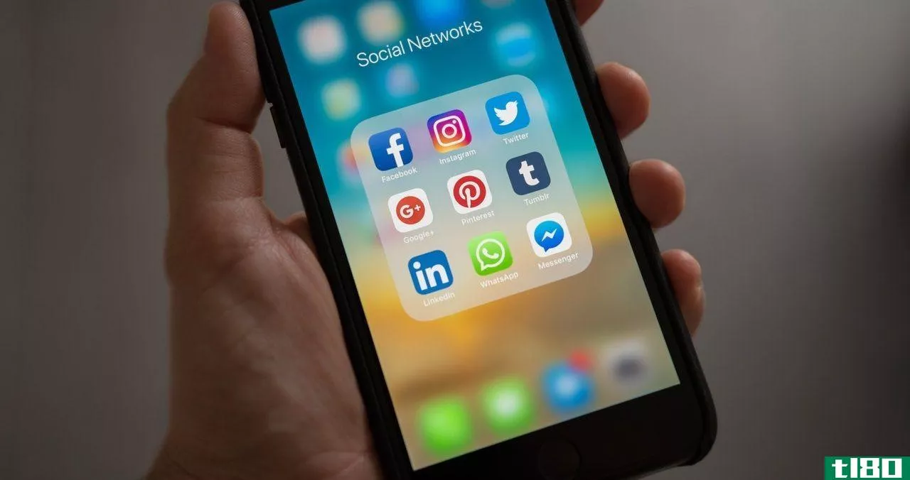 A hand holding a phone with social media apps