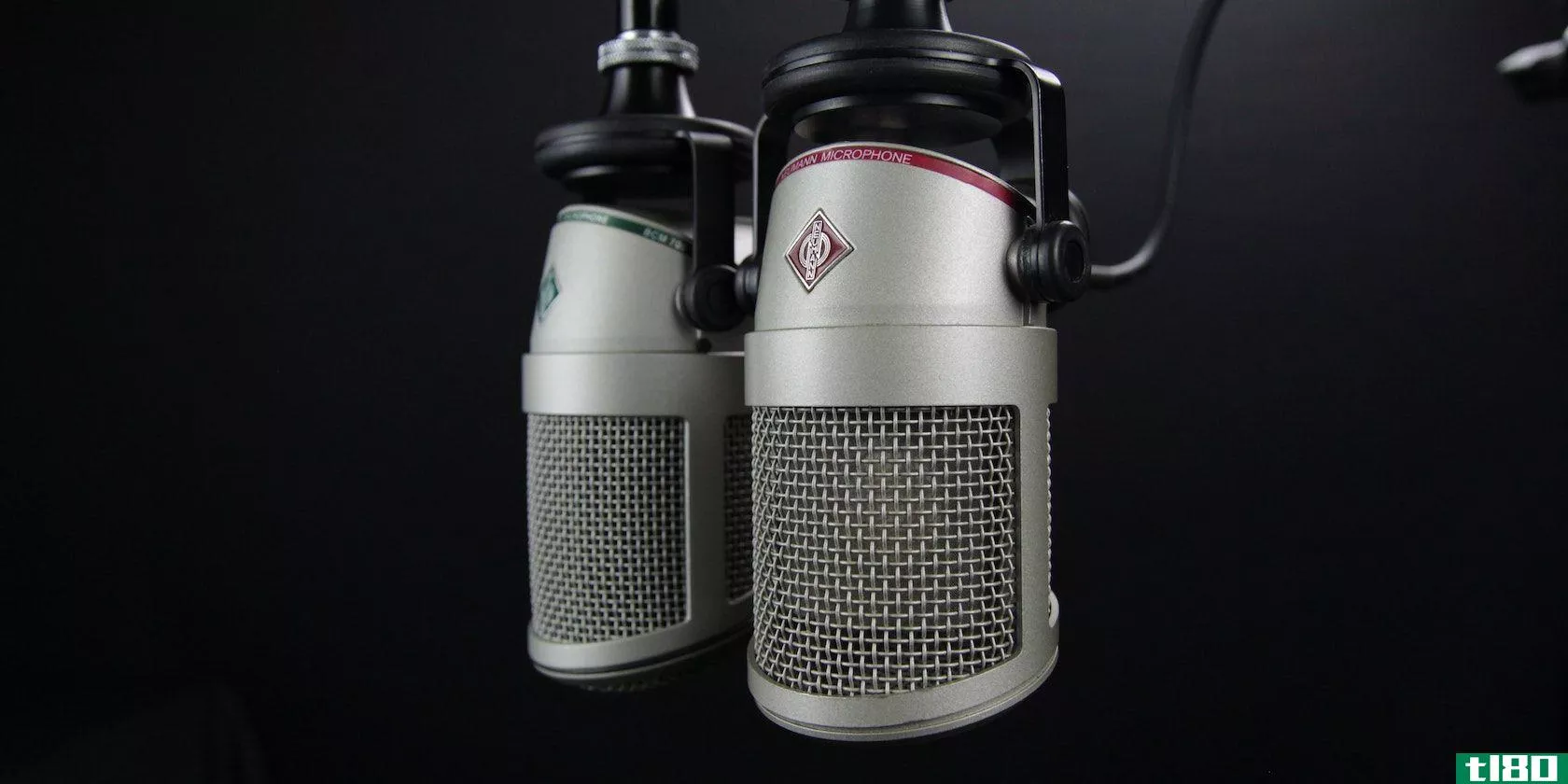 Two gray condenser microphones side by side with a black background