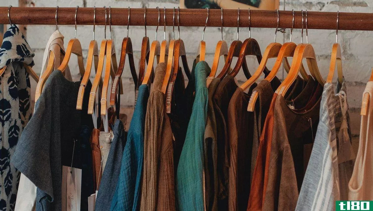 assorted clothing of different colours hanging from a tan brown clothes rack