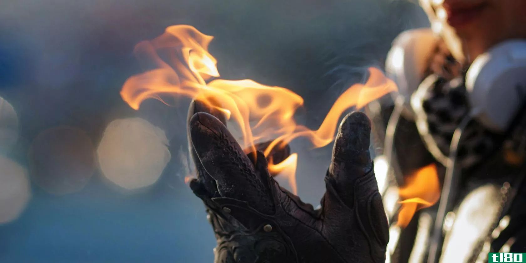 a person weraing headphones holds fire in a gloved hand