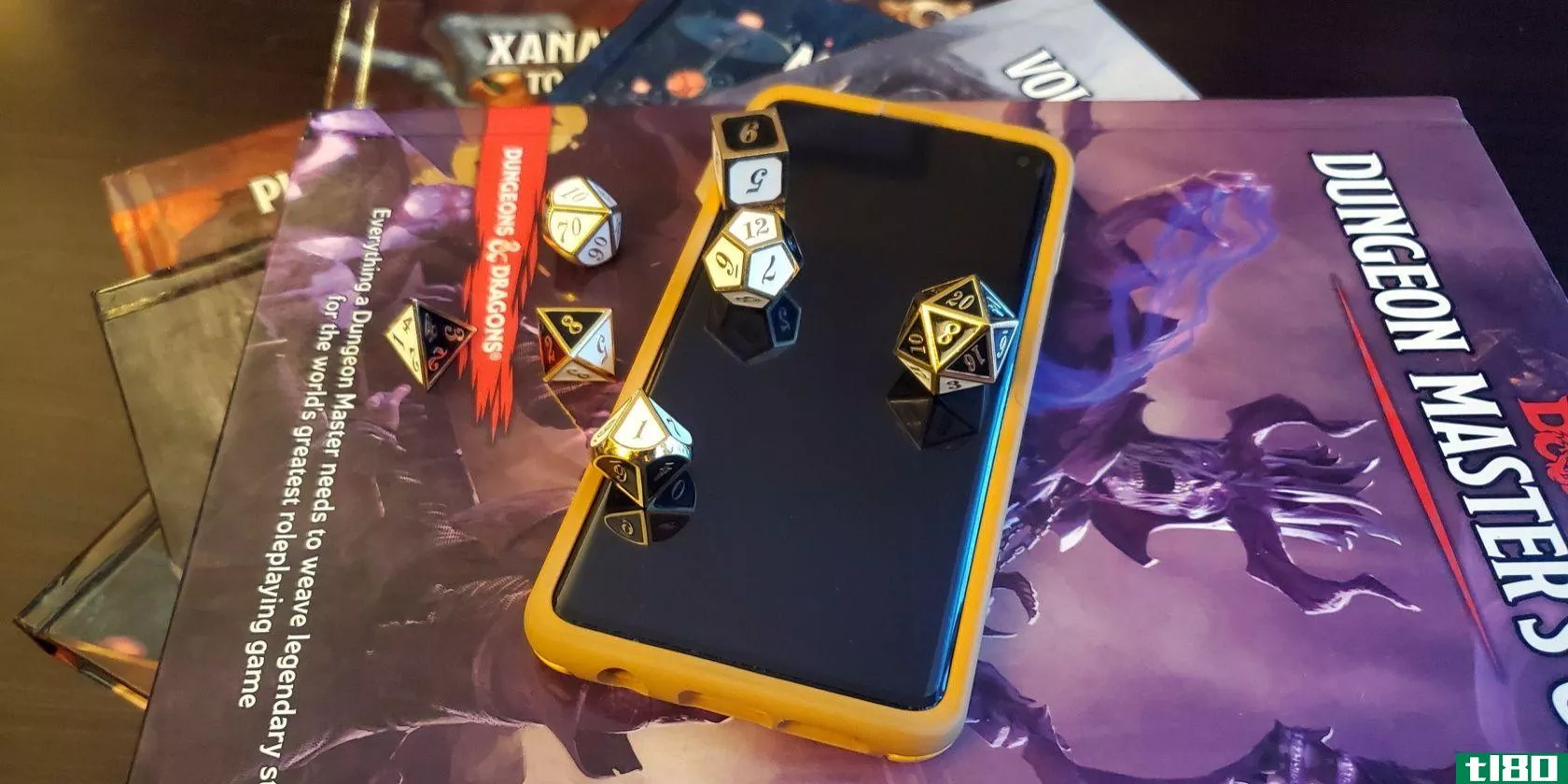 an android phone sits on top of some dunge*** and drag*** rulebooks, with a set of polyhedral dice scattered over it.
