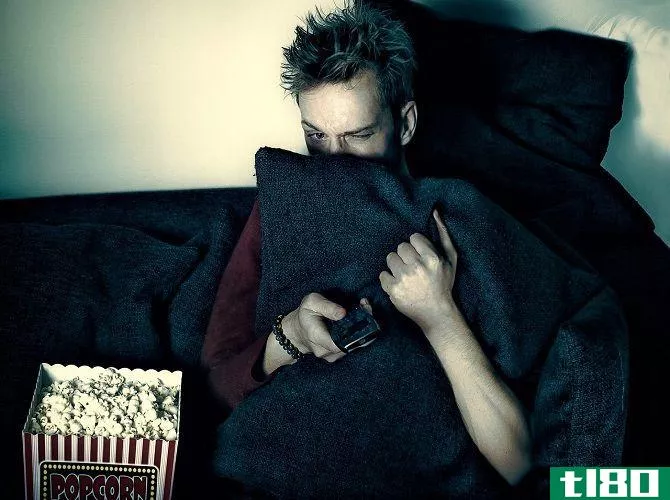 Man watching TV behind a pillow