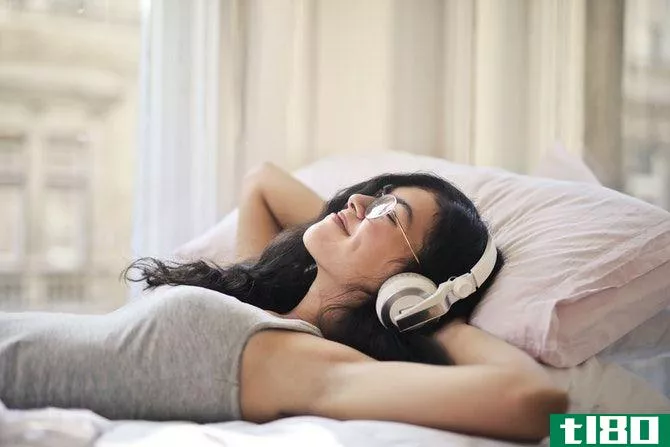 woman relaxing on bed with headphones on