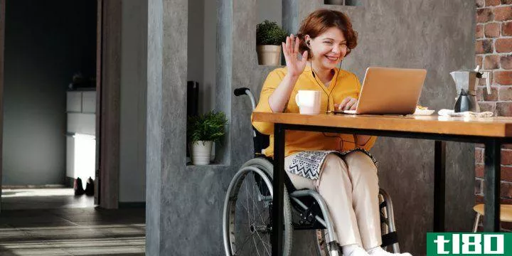 A woman waving hello to someone on a computer screen