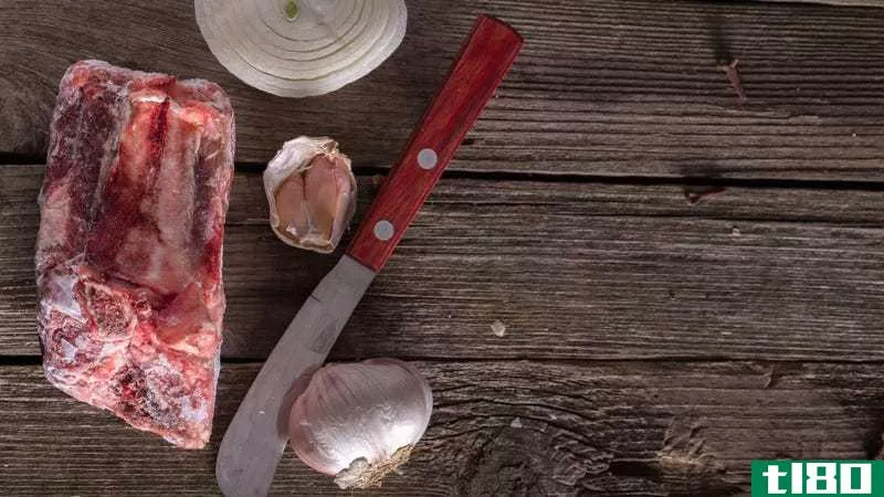 A frozen cut of meat on a rustic wood table