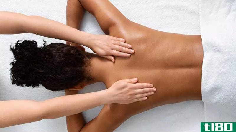 A woman lies facedown and receives a massage
