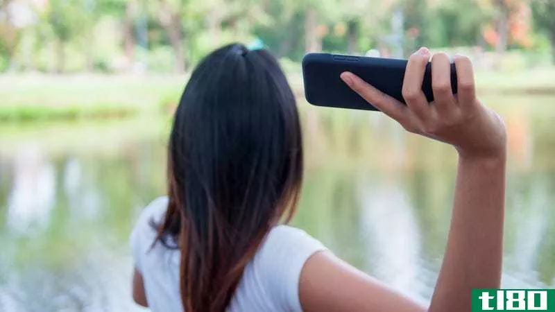 A woman raises her arm to throw her phone into a lake