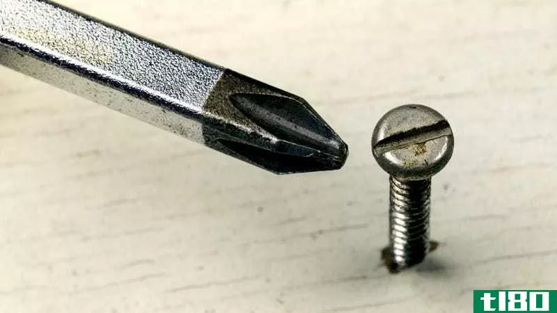 A Phillips head screwdriver near a screw it won't fit into