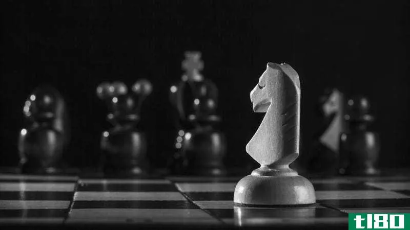 A white knight chess piece faces down a row of black pieces