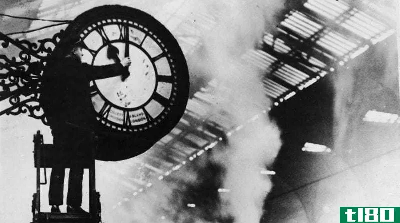 A man changes the time on an old-fashioned train station clock