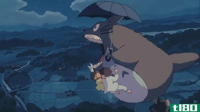 In a still from My Neighbor Totoro, Totoro flies through the air with an umbrella.