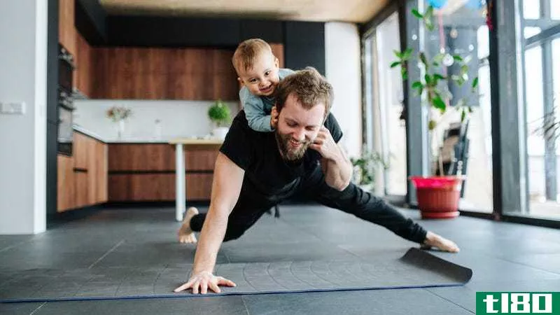 dad doing one-armed pushups in the kitchen with kid on back